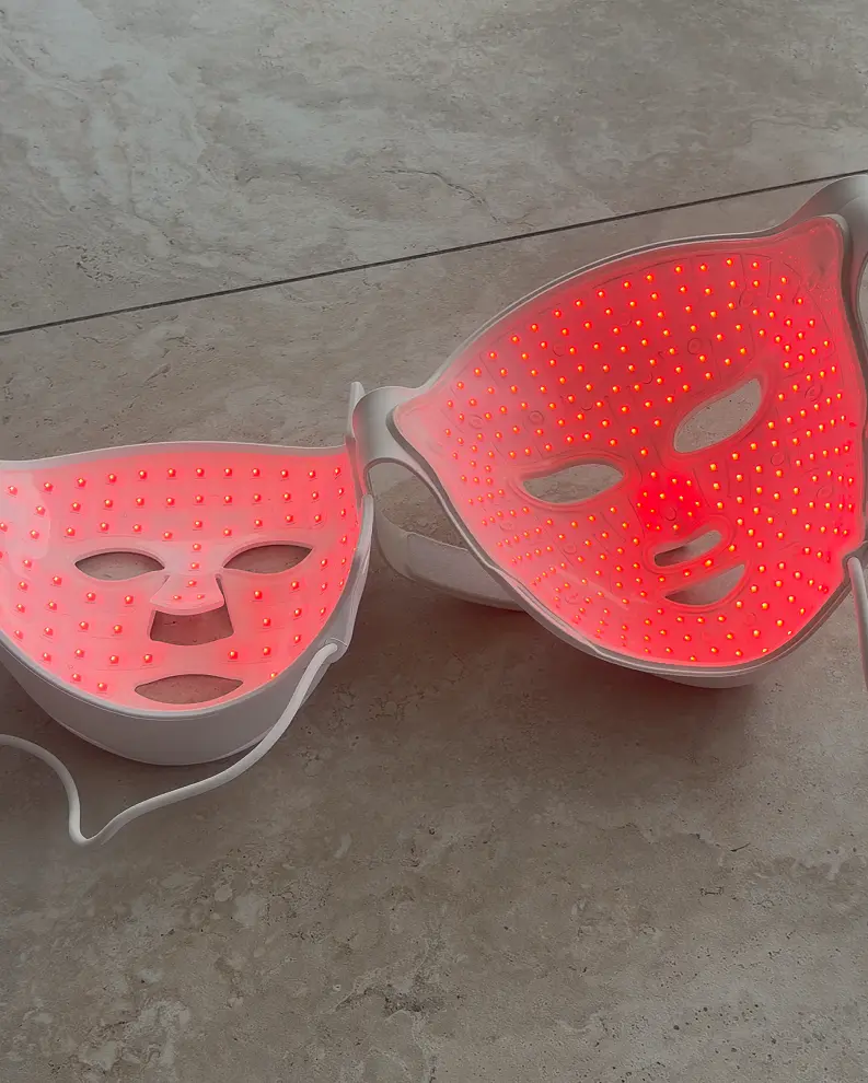 Two LED masks lit in red on a stone floor, one with widely spaced diodes and the other with far denser ones