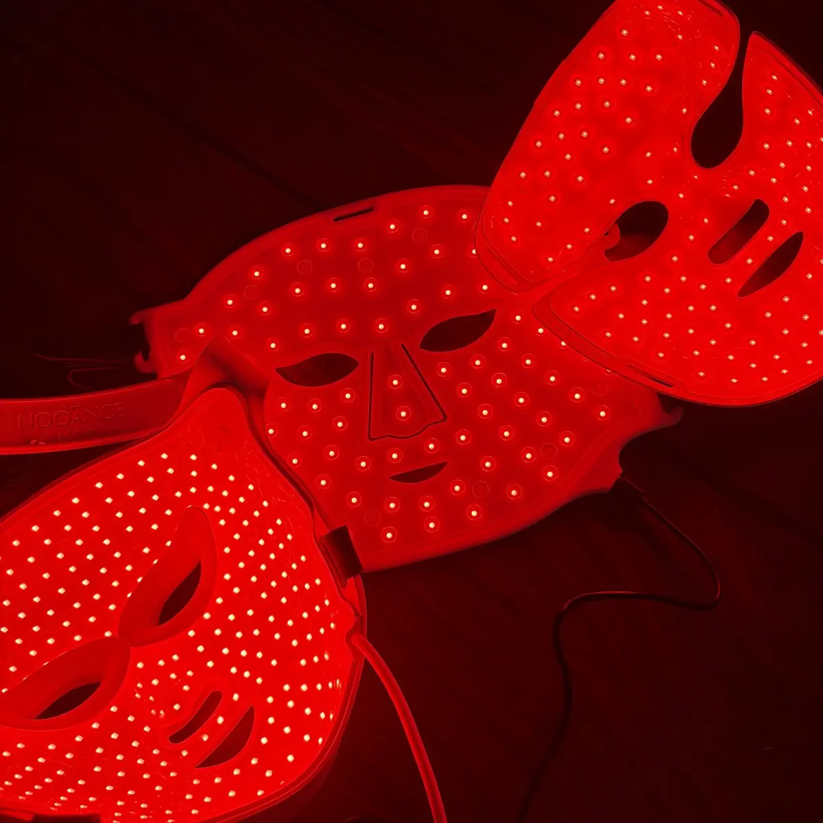 Three LED masks lit red side by side, each with visibly different spacing between the diodes