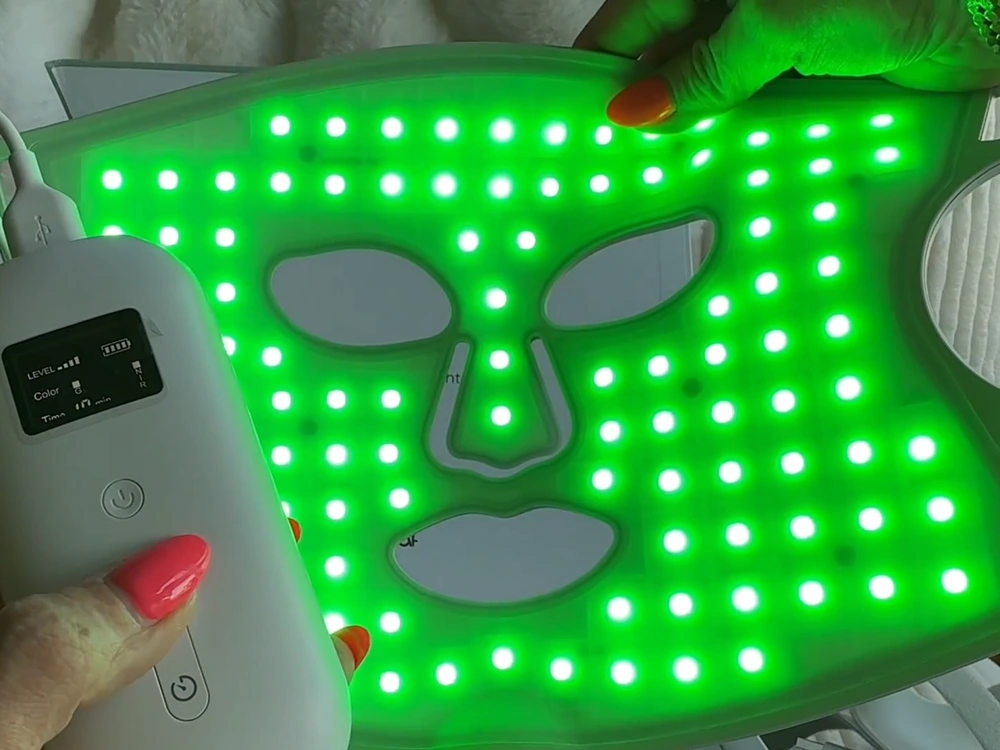 Nanoleaf LED mask lit in green mode with the same grid of lit points across the forehead and cheeks