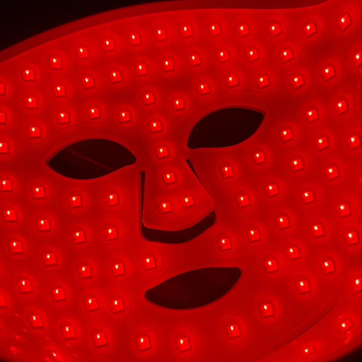 Close-up of the lit CurrentBody Series 2 mask showing the spacing between LEDs and the bare cutouts at the eyes, nose and mouth