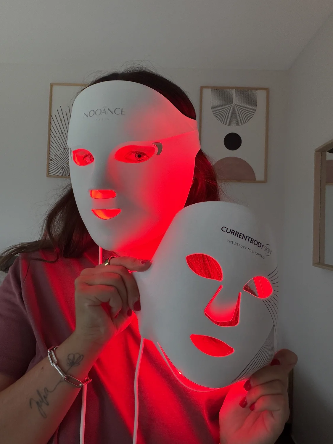 Emilie wearing the lit Nooance Elite X600 LED mask while holding the lit CurrentBody Series 2 in her hand