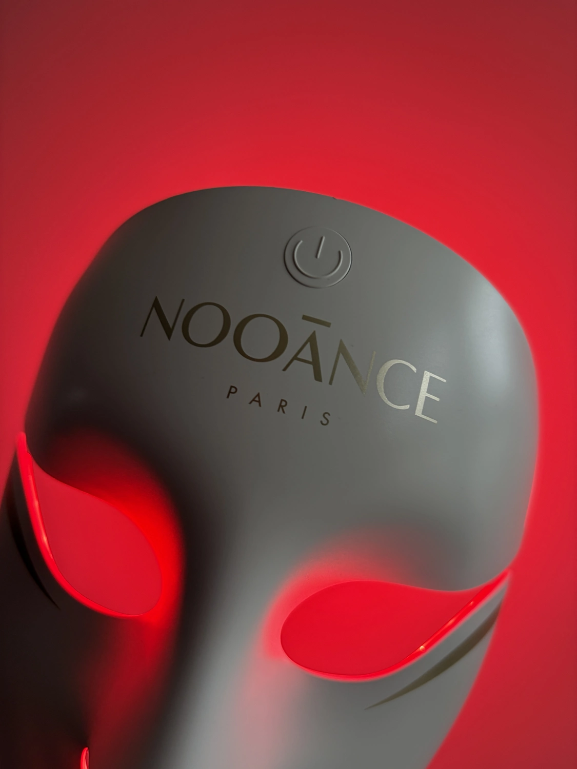 Close-up of the forehead of the Aurion X252 LED mask with the single power button above the Nooance logo