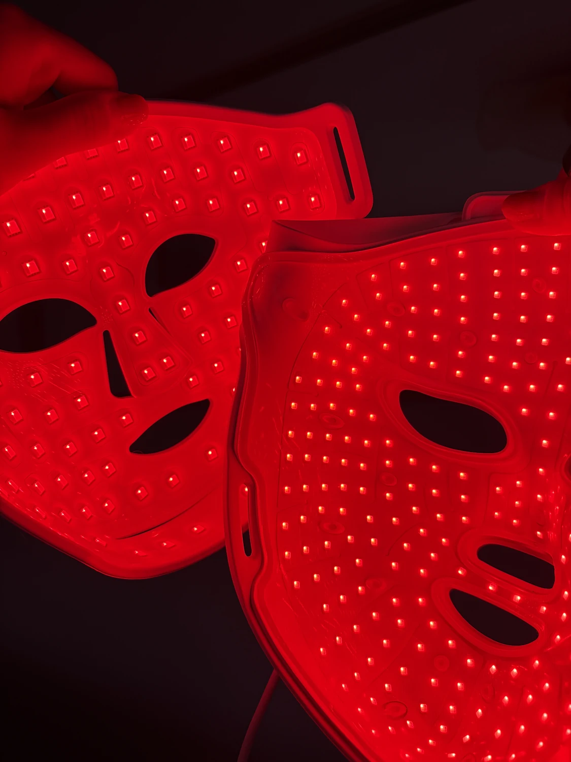 Close-up of the two lit LED arrays, the CurrentBody Series 2 with widely spaced square emitters and the Nooance Elite X600 with a tight grid of small light points